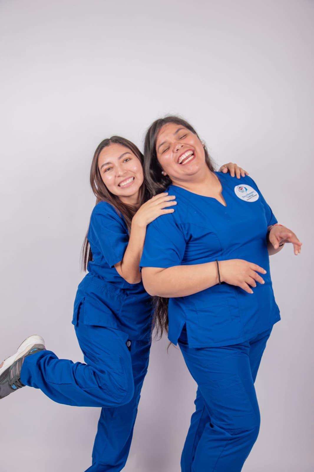 Two nurses laughing together — happy colleagues in a care setting